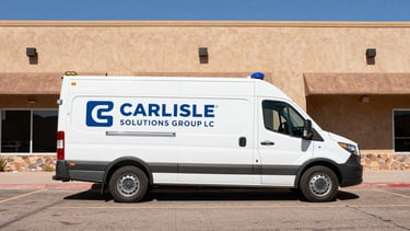 Wide, high-contrast shot of a branded CARLISLE SOLUTIONS GROUP LLC service vehicle, clean and modern, parked in front of a commercial building in Santa Fe, bright desert daylight, sharp shadows, industrial editorial style.