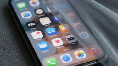 A symbolic image of a smartphone screen showing blurred social media icons, partially covered by a translucent cool grey fabric, suggesting the complexity of digital hiding.