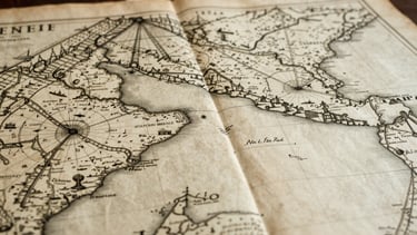 Wide panoramic shot of a detailed 18th-century Atlantic navigation map, aged parchment, soft diffused library light, macro detail of cartography.