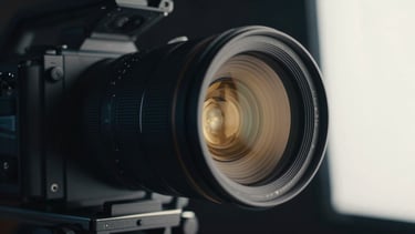 Cinematic close-up of a high-end studio camera lens reflecting warm gold lights, dark background, professional broadcasting setup.