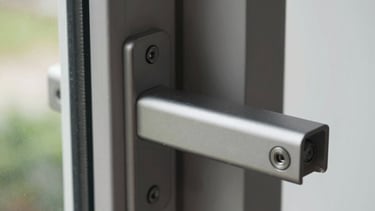Tampilan close-up dari kusen jendela aluminium matte berkualitas tinggi dengan sistem penguncian modern di sebuah bangunan kontemporer Asia Tenggara.