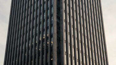 Architectural detail of a modern financial capital skyscraper in Zurich, soft morning window light, muted navy and warm gray tones, 35mm photography