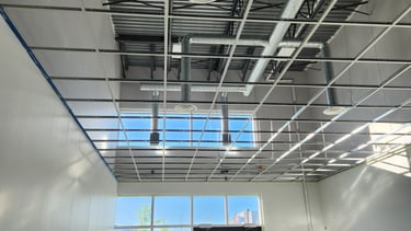 Commercial suspended ceiling grid installation with exposed T-bar system and lighting infrastructure