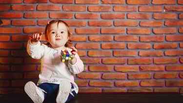 a little girl sitting on a table with a rubt toy
