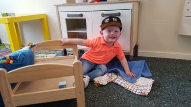 a young boy sitting on the floor in a playroom