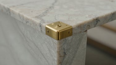Close-up of premium marble slab installation with brushed brass joint detail, soft side lighting, focus on precision craftsmanship.