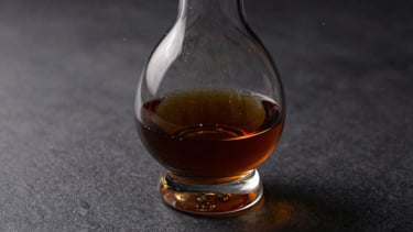 A crystal decanter filled with dark aged cognac on a graphite surface, soft side lighting