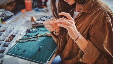 Una artesana creando collares y pulseras hechos a mano en un taller creativo.