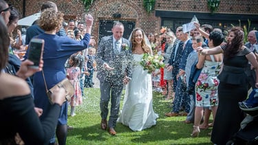 newly-wed running through confetti being thrown by guests