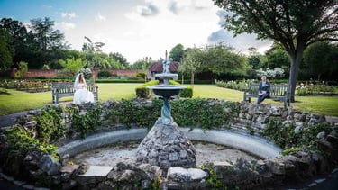 newly-weds sitting on either side of a water fountain
