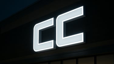 Wide environmental photograph of a large illuminated 3D sign mounted on a retail exterior at night, cool white light, sharp edge detail on acrylic and aluminum channel letters, no people