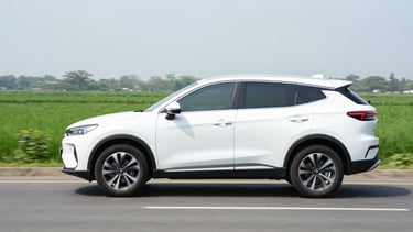 Side view of a modern clean SUV driving on a bright open highway in Vietnam, daylight, crisp green landscape in background