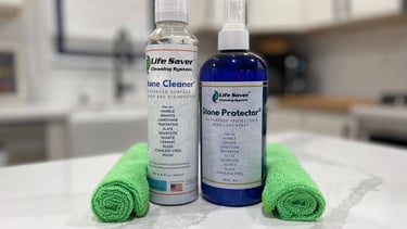 Life Saver Stone Cleaner and Stone Protector bottles with green microfiber cloths on a marble countertop.