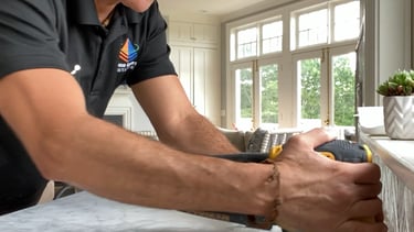 Professional contractor using a power sander to restore and hone a white marble countertop.