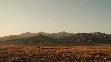 Wide panoramic Wyoming landscape at golden hour, rugged mountains and expansive sky, warm earthy tones, low horizon, soft morning window light.
