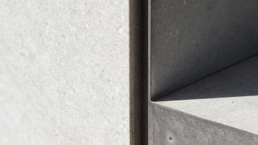 Macro detail shot of a sharp shadow-gap join between raw steel and hand-aligned travertine, crisp natural daylight, high-contrast, editorial architectural photography.