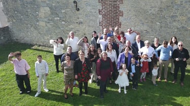 A large multi-generational group of people waving and smiling for a family photo outdoors.