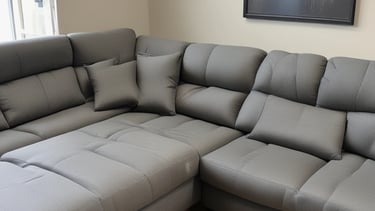 A technician gently cleaning a cozy upholstered sofa in a bright living room.