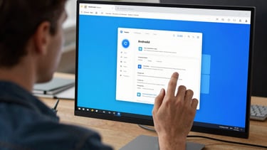 An over-the-shoulder shot of a designer working on an Android UI project on a large high-resolution monitor. The screen displays a palette of bright blue and clean whites. North American office setting.