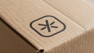 Close-up of a high-quality finished corrugated box with a clean, minimalist brand logo printed in black ink. The lighting is crisp and detailed, showing the paper texture.