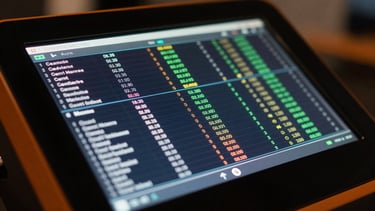 Close-up macro shot of a glowing digital media terminal screen displaying live data tables, high-contrast, dark background with orange accents