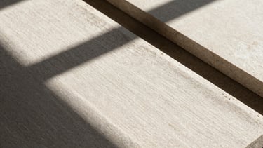 Close-up of tactile design materials, raw linen and limestone under harsh direct sunlight with sharp dramatic shadows, neutral tones, 35mm lens