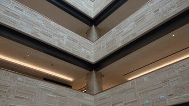 Photo of a modern lobby with complex multi-level drywall ceilings and hidden steel blue lighting. High contrast, architectural detail.