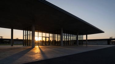 Wide sweeping architectural perspective of a modern concrete and glass pavilion at sunset, dramatic low-key shadows, golden reflections, 35mm