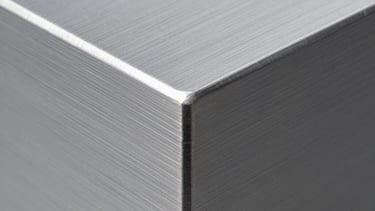 Macro photography of a brushed aluminum surface with a clean, sharp edge. Industrial precision, soft grey gradients, and studio lighting.