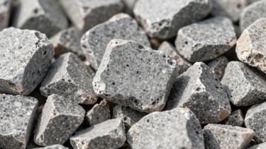 Macro photography of crushed limestone aggregate, showing varied light gray textures and sharp edges, used in heavy-duty North American road paving.