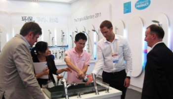 Professional team testing modern bathroom shower heads and faucets at a sanitary ware trade show.