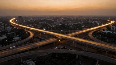 Aerial wide-angle view of a massive multi-level highway interchange in India during golden hour, with glowing saffron and gold digital twin vector lines tracing the lanes, high-contrast architectural lighting