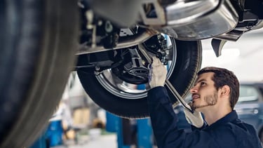Mechanic doing repairs underneath a car in a workshop