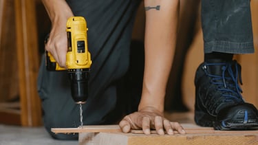 Carpenter drilling holes in wood with a drill machine