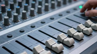 Detailed shot of sound mixing console faders in a high-tech studio. Pale blue lighting reflecting on the metallic surfaces. Atmosphere of precision and focus.