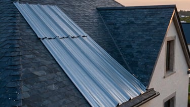 A professional architectural photograph of a high-quality slate and zinc roof on a French house. The shot is taken during the golden hour in a Western European / French residential area, highlighting the artisanal texture of the materials and precise installation. The palette uses deep dark blue and steel blue tones to emphasize durability and expertise.