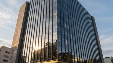 A wide photography shot of a modern, luxury corporate office building in Bogotá, Colombia, with a sleek glass facade reflecting the morning sun, professional atmosphere, navy blue and gold ambient tones.