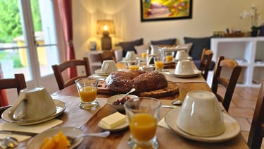 la ramade, table de la salle à manger dressée du petit-déjeuner, grosse brioche, confiture et jus .