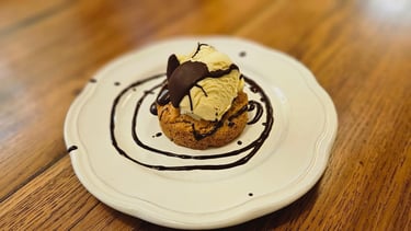 Dessert avec un biscuit au amande dessus un boule de glace vanille et chocolat fondu.