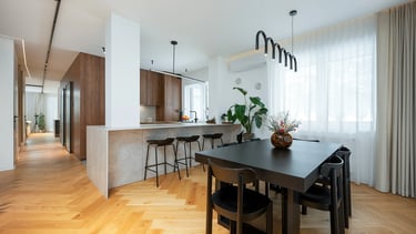 Nowoczesna kuchnia z wyspą i stołem jadalnym, drewniana podłoga, duże okno z zasłonami