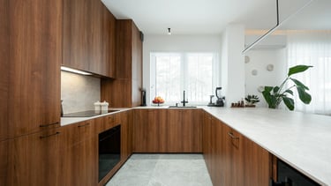 Nowoczesna kuchnia w kształcie U z drewnianymi frontami i jasnym blatem.