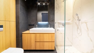 Nowoczesna łazienka z umywalką w drewnianej szafce, lustrem i przeszklonym prysznicem