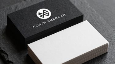 An elegant stack of business cards on a dark slate surface, featuring a minimalist white logo with premium matte finish, North American style.