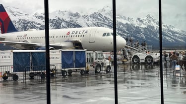 A Delta Airlines plane at the Jackson Hole, WY airport with the Tetons in the background.