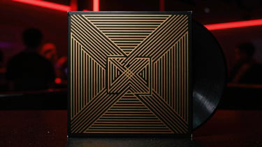 Dark minimalist vinyl record sleeve, gold metallic geometric pattern, high-contrast black background, atmospheric lighting