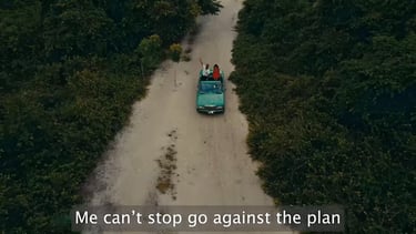 a aqua green car driving down a dirt road with 2 people on it with shrubbery bush on the sides