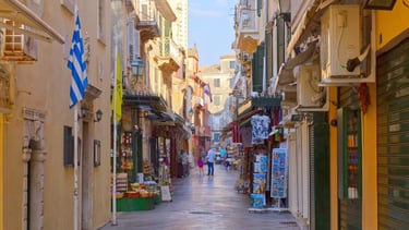 Centro histórico de Corfu com lojas abertas e movimento típico de dias com navios atracados.