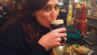 Foto da autora no pub comendo e bebendo em Dublin.