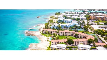 Vista aérea de Grand Cayman, destacando os grandes resorts à beira-mar e o litoral da ilha.