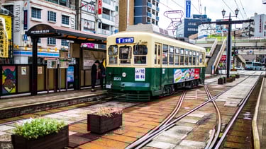 Tram elétrico de Nagasaki parado na estação, pronto para transportar passageiros pelo centro histórico.